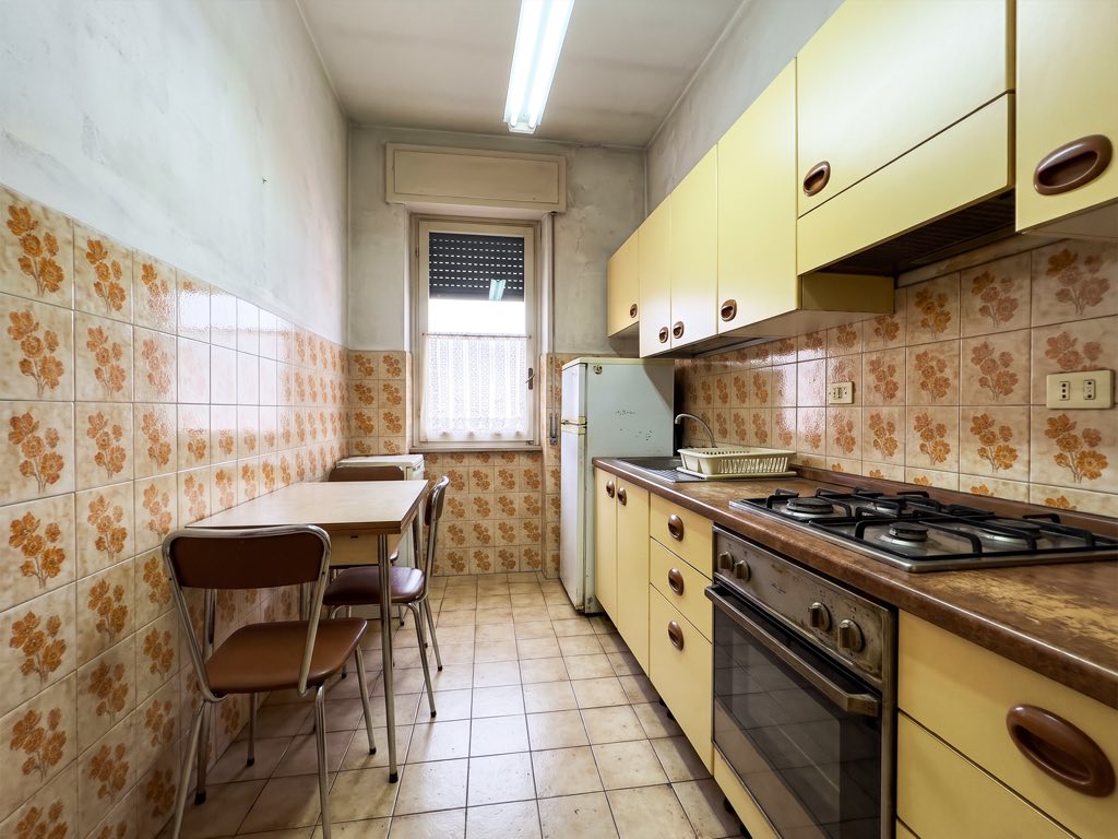 Prima: cucina datata con piastrelle a fiori e mobili gialli.